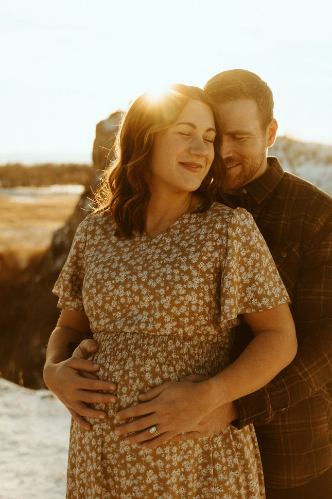 Couple posing for winter maternity photos in Montana during sunset