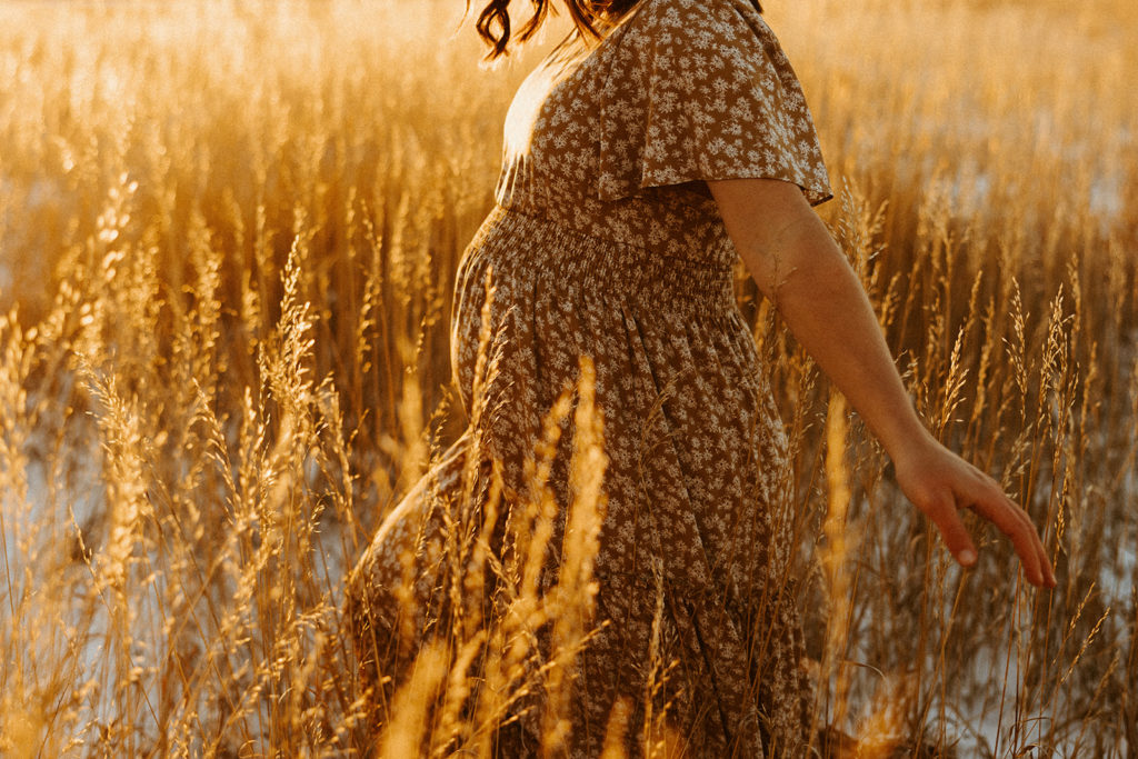 Woman standing in a Montana field and posing for maternity photos