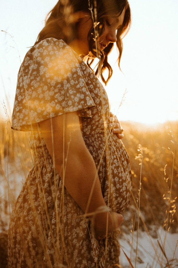 Mother to be posing for winter maternity photos in Montana during sunset