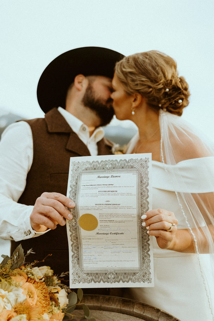 bride and groom holding up signed marriage certificate