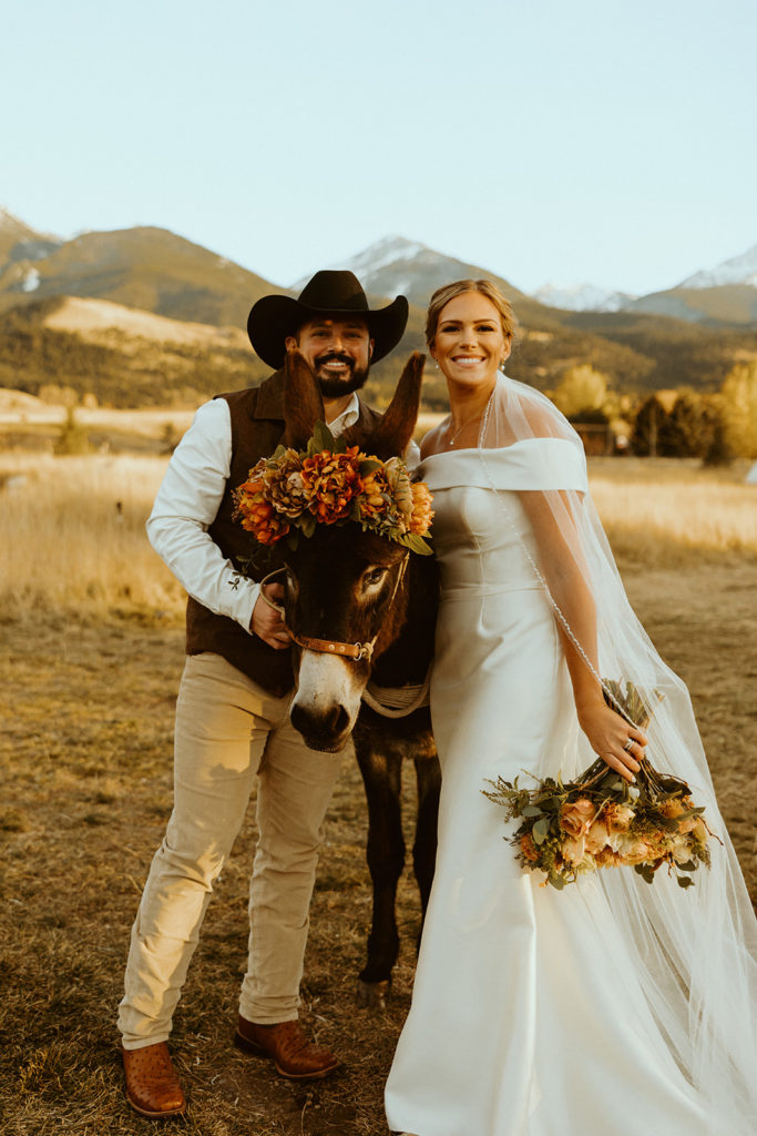 bride and groom posing with a donkey during their montana paradise valley wedding