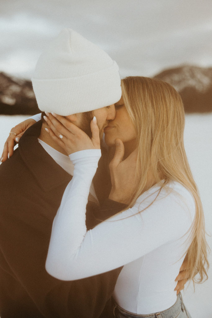 Couple posing for intimate winter engagement photos in the mountains